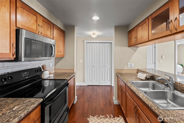 kitchen featuring brown cabinets, stainless steel microwave, a sink, and black range with electric stovetop