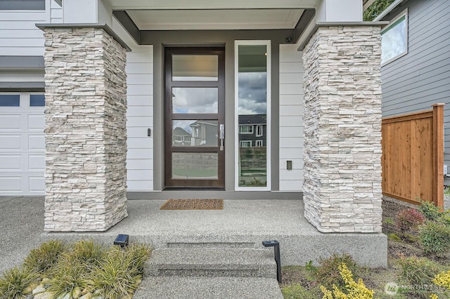 doorway to property with covered porch, fence, and stone siding