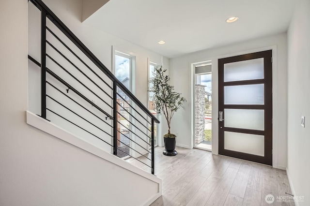 entryway featuring light wood finished floors, a wealth of natural light, and stairway