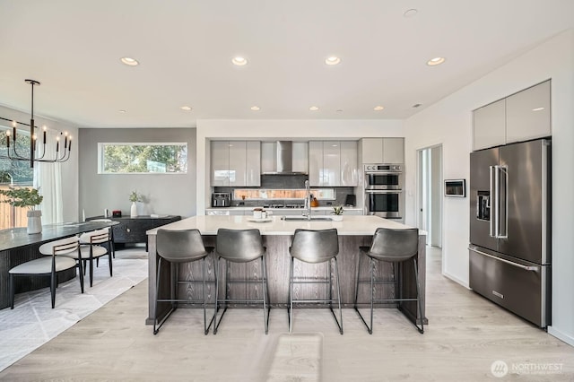 kitchen with gray cabinetry, appliances with stainless steel finishes, wall chimney exhaust hood, and modern cabinets