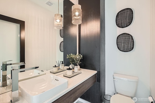 bathroom with a sink, visible vents, and toilet
