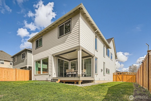 rear view of house featuring a fenced backyard and a lawn