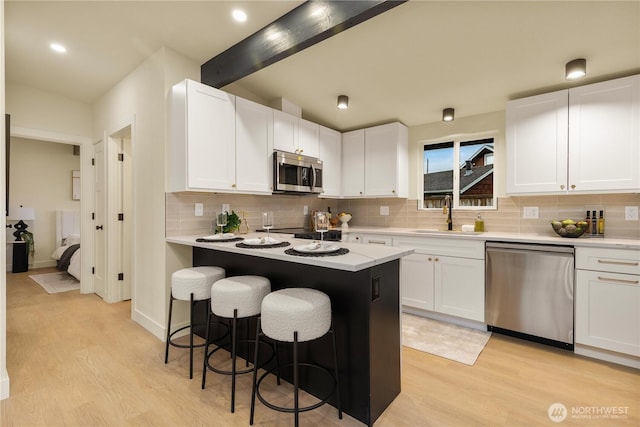 kitchen with a kitchen bar, a sink, light wood-type flooring, and appliances with stainless steel finishes