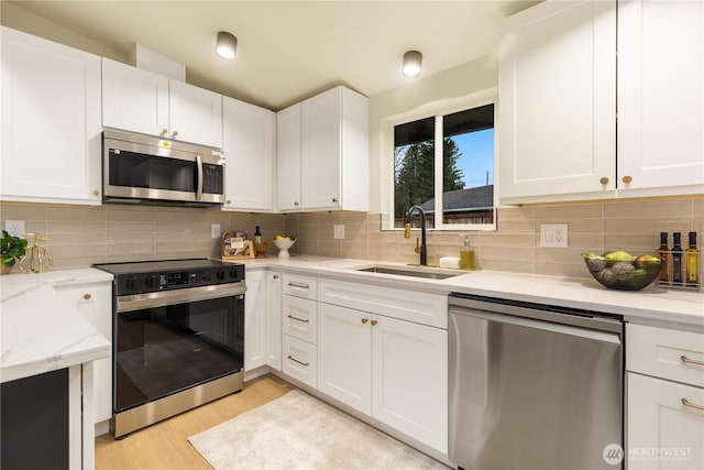 kitchen featuring white cabinetry, a sink, backsplash, and appliances with stainless steel finishes