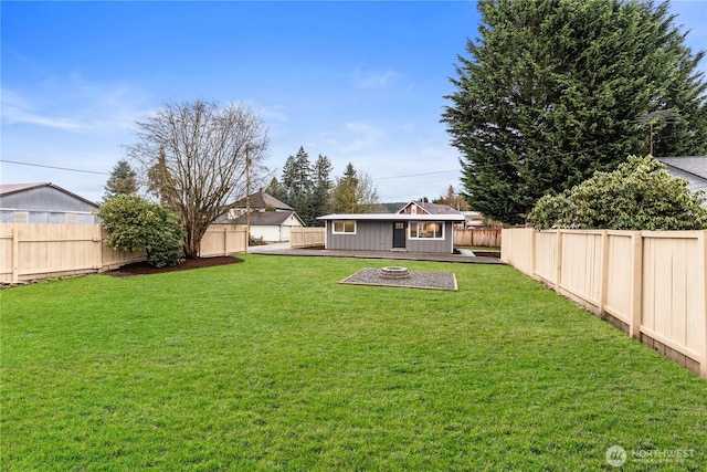 view of yard with a fenced backyard, an outdoor fire pit, and an outdoor structure