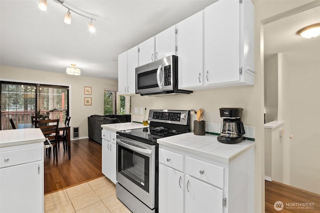 12427 129th Ave E, Puyallup, WA 98374 - kitchen featuring tile counters, light tile patterned floors, white cabinets, track lighting, and appliances with stainless steel finishes