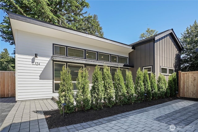 back of property with fence, board and batten siding, and a patio area