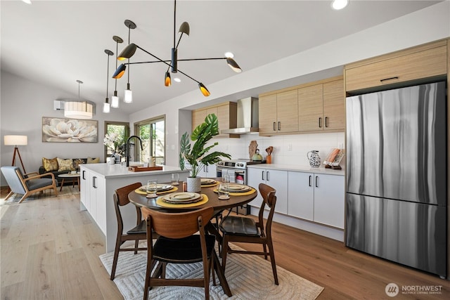 dining room featuring light wood-style flooring, recessed lighting, vaulted ceiling, and a chandelier