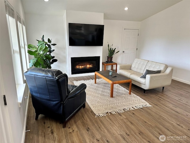 living area featuring recessed lighting, wood finished floors, and a glass covered fireplace