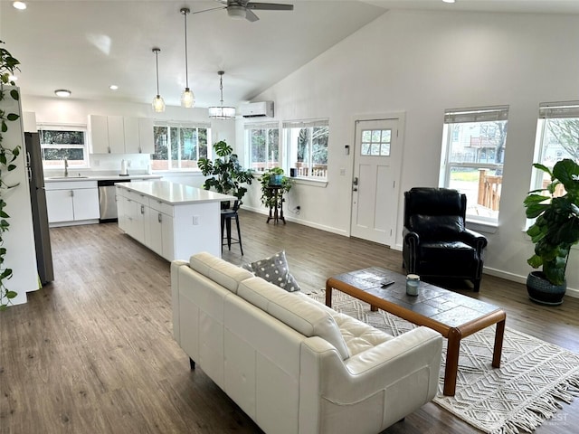 living area with a ceiling fan, a wall unit AC, baseboards, and wood finished floors