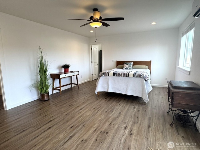 bedroom featuring baseboards, wood finished floors, a wall unit AC, and recessed lighting