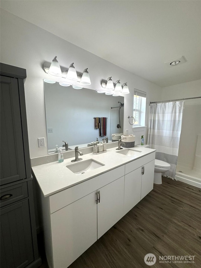 bathroom with toilet, a sink, a shower with shower curtain, and wood finished floors