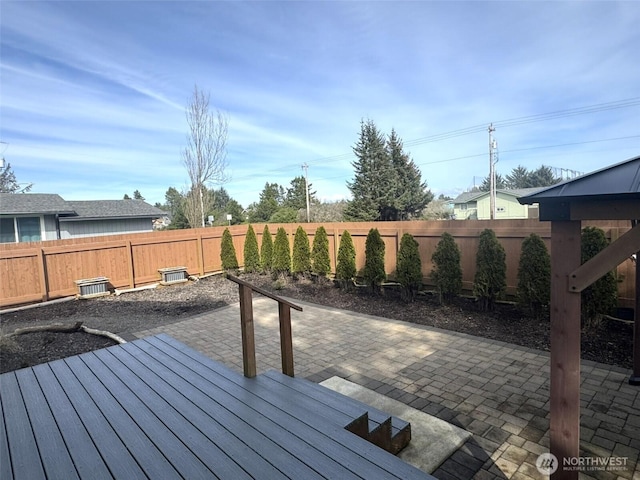 wooden terrace with a fenced backyard and a patio
