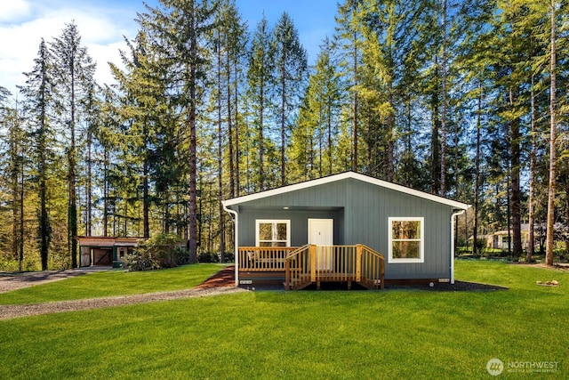 exterior space with an attached garage, driveway, a front yard, and an outbuilding