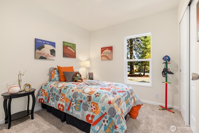 carpeted bedroom featuring baseboards and a closet
