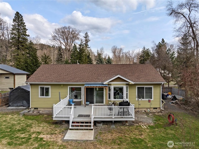 rear view of house featuring crawl space, a yard, a deck, and fence