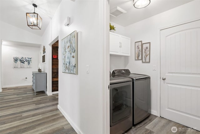 washroom with cabinet space, baseboards, washing machine and dryer, and wood finished floors