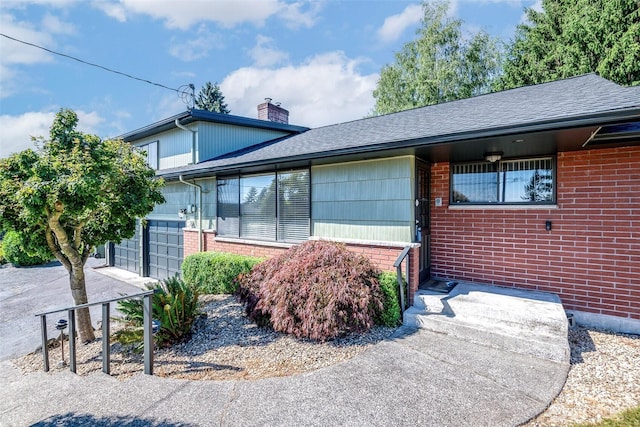 2302 126th Avenue Ct E, Edgewood, WA 98372 - view of side of home with brick siding, a chimney, a shingled roof, and a garage