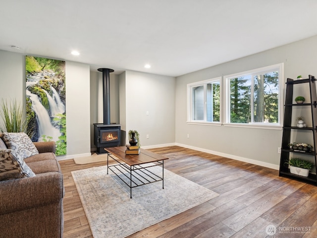 living room with recessed lighting, light wood finished floors, baseboards, and a wood stove