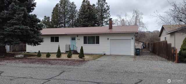 single story home featuring metal roof, fence, a chimney, a garage, and driveway