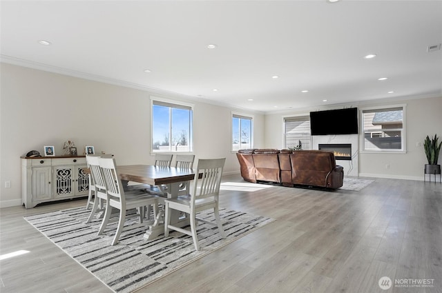 dining area with baseboards, light wood-style flooring, and crown molding