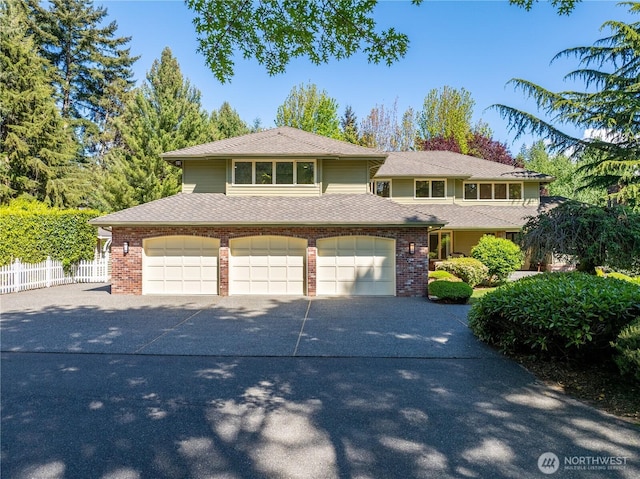 view of front of home with driveway, fence, a garage, and brick siding