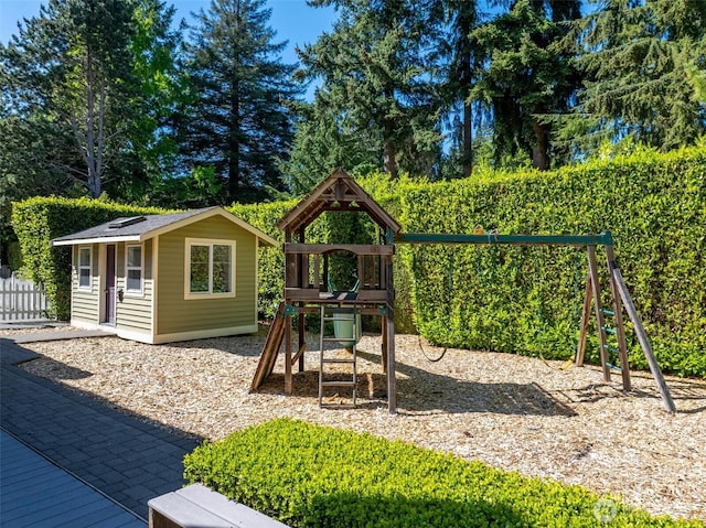 view of jungle gym with fence, an outdoor structure, and view of scattered trees