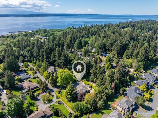 view of property location with a large body of water, nearby suburban area, and a forest