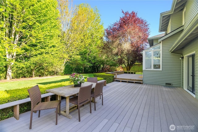wooden deck featuring outdoor dining area and a lawn