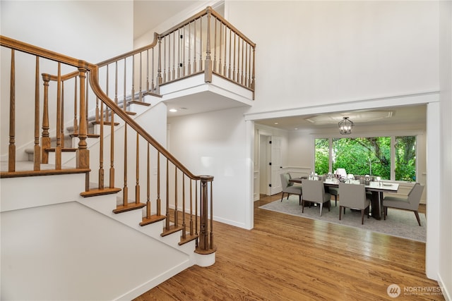 stairway featuring wood finished floors and a towering ceiling