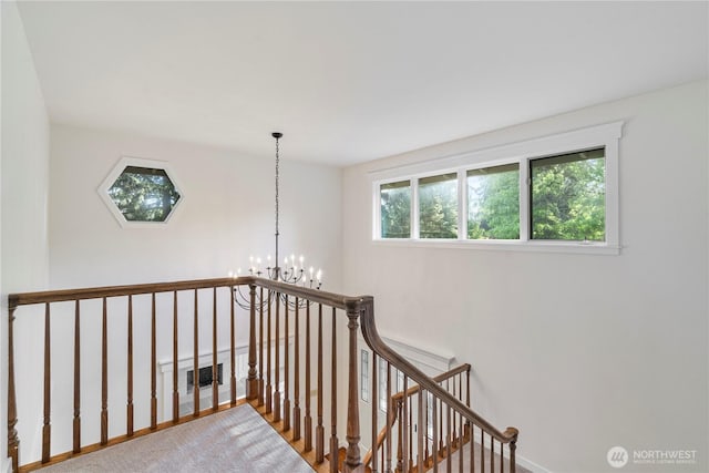 hall with an upstairs landing, a chandelier, and baseboards
