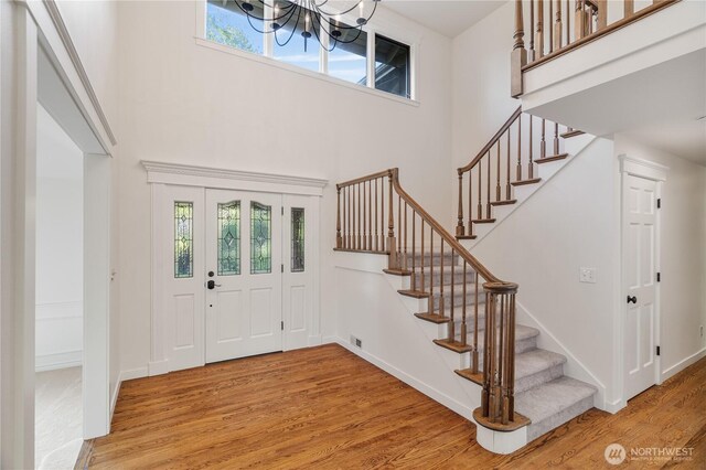 entrance foyer with wood finished floors, a high ceiling, stairway, a chandelier, and baseboards