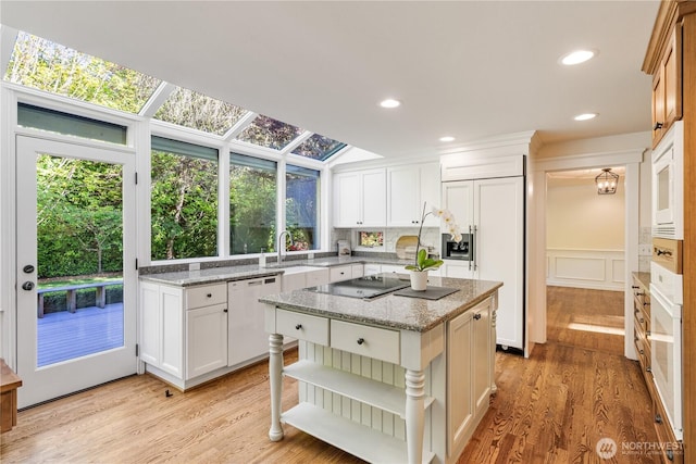 kitchen with built in appliances, light wood-type flooring, a sink, white cabinetry, and recessed lighting