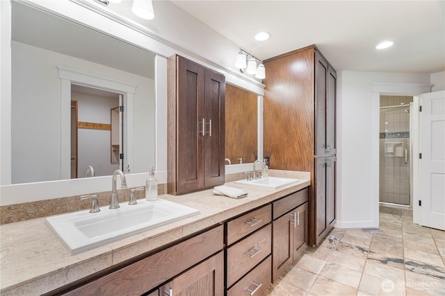 bathroom with double vanity, tiled shower, and recessed lighting