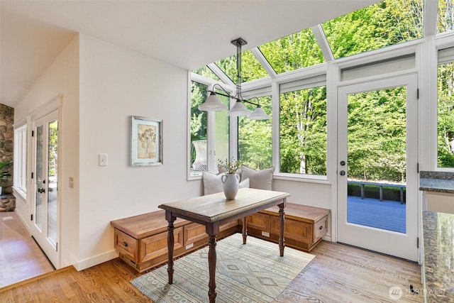 sunroom / solarium with wood finished floors, healthy amount of natural light, a wooden deck, and vaulted ceiling