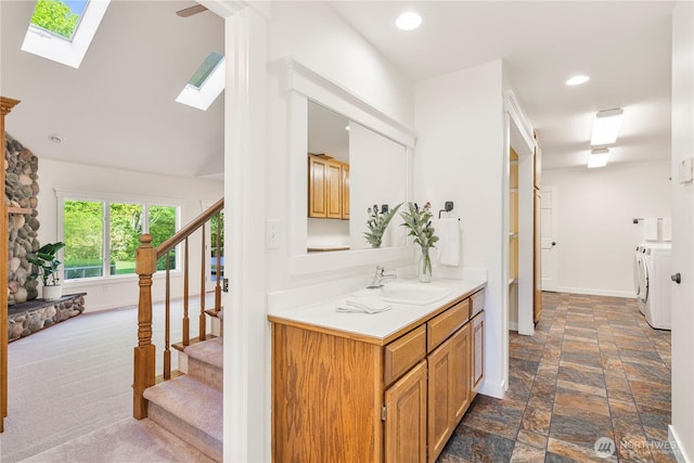 bathroom with independent washer and dryer, a skylight, baseboards, vanity, and stone finish flooring