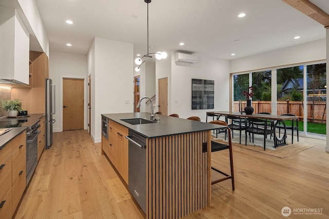 kitchen featuring stainless steel appliances, a sink, dark countertops, modern cabinets, and a wall mounted air conditioner