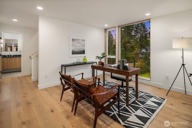 office area featuring baseboards, light wood-style floors, a wall of windows, and recessed lighting