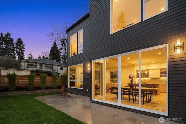 back of property at dusk featuring fence and a patio area