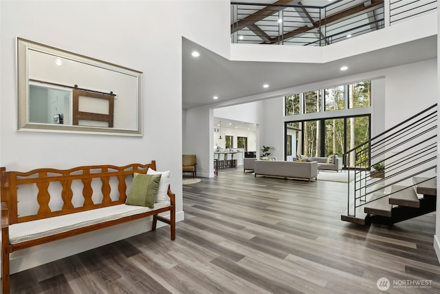 foyer entrance featuring stairway, recessed lighting, baseboards, a towering ceiling, and wood finished floors