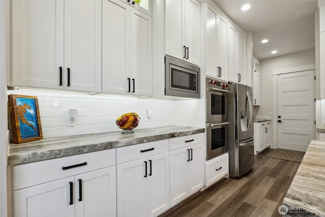 kitchen featuring stainless steel appliances, recessed lighting, white cabinetry, light stone counters, and dark wood-style floors