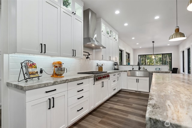 kitchen featuring dark wood finished floors, decorative backsplash, a sink, stainless steel gas stovetop, and wall chimney exhaust hood