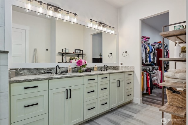 bathroom with a spacious closet, double vanity, and a sink