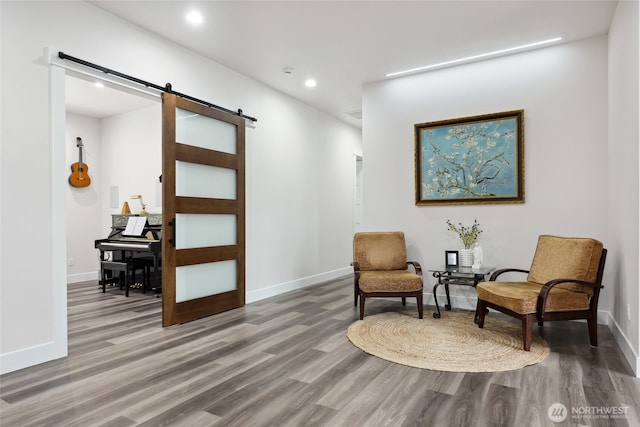 living area with recessed lighting, baseboards, a barn door, and wood finished floors