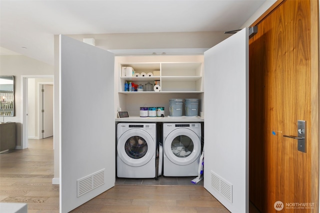 clothes washing area featuring light wood-style flooring, visible vents, and independent washer and dryer