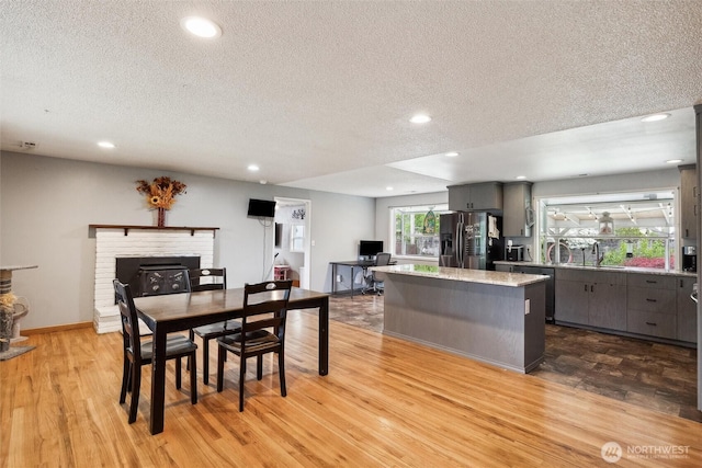 dining space with a brick fireplace, recessed lighting, and a textured ceiling
