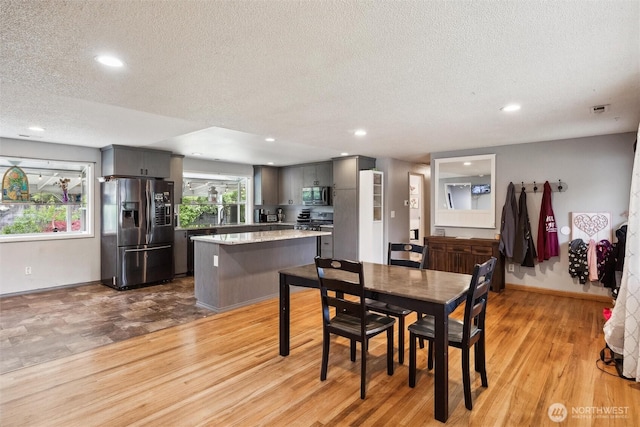 dining space featuring baseboards, recessed lighting, a textured ceiling, and light wood finished floors