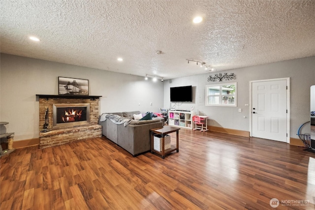 living area with a brick fireplace, wood finished floors, recessed lighting, a textured ceiling, and rail lighting