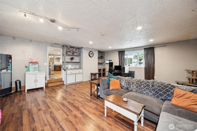 living room with recessed lighting, a textured ceiling, and wood finished floors