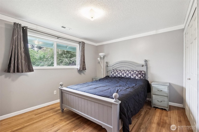 bedroom featuring ornamental molding, a textured ceiling, and wood finished floors